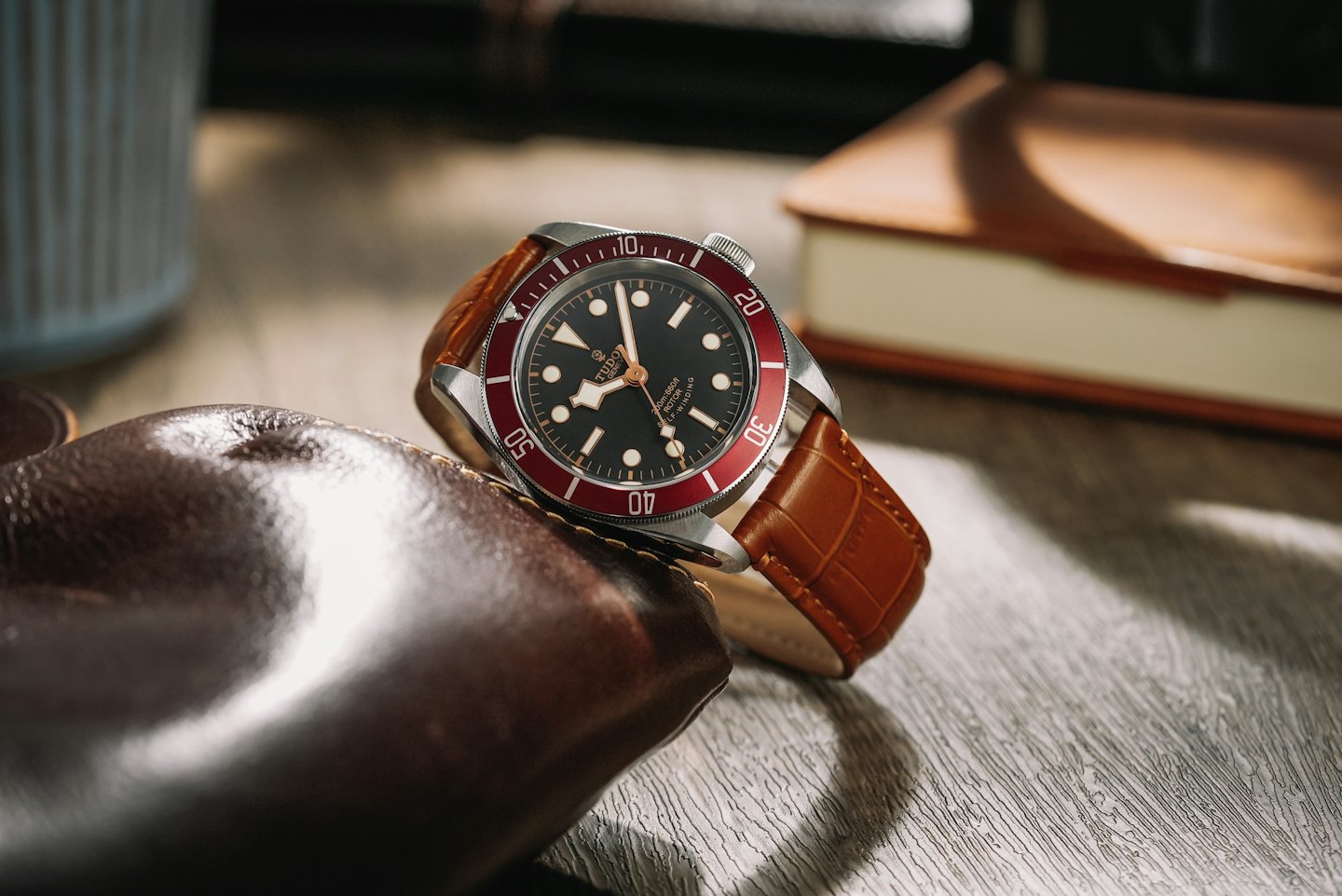 Luxury wristwatch with a brown strap on a wooden surface.