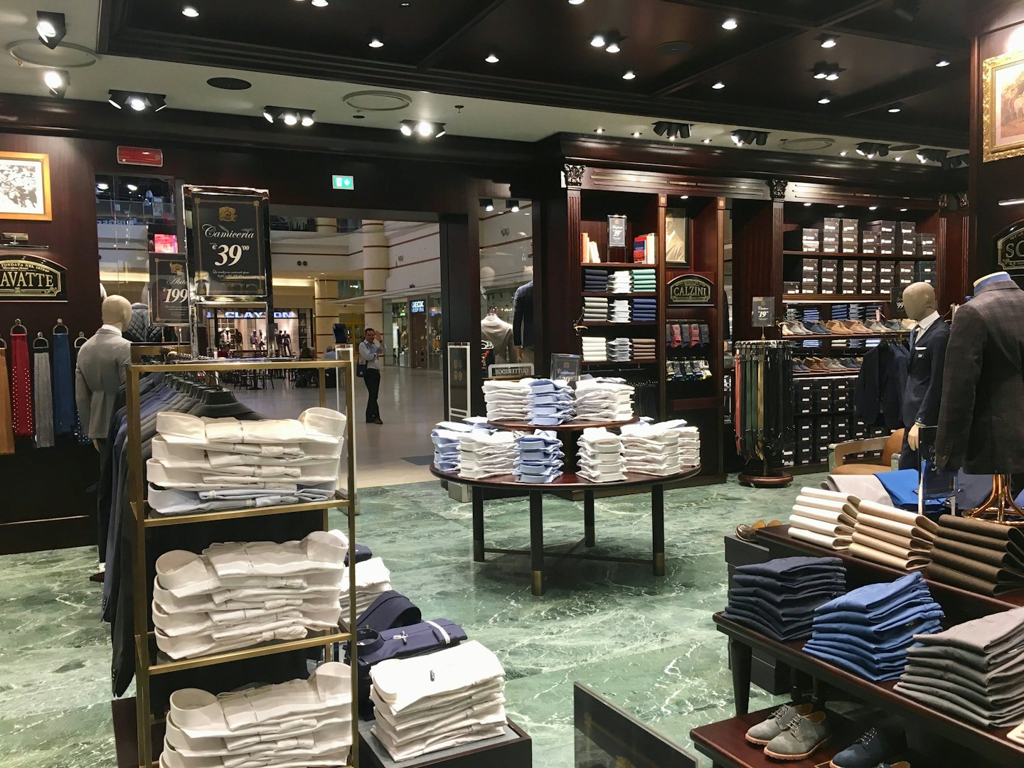 Men's clothing store displays suits, shirts, and accessories.