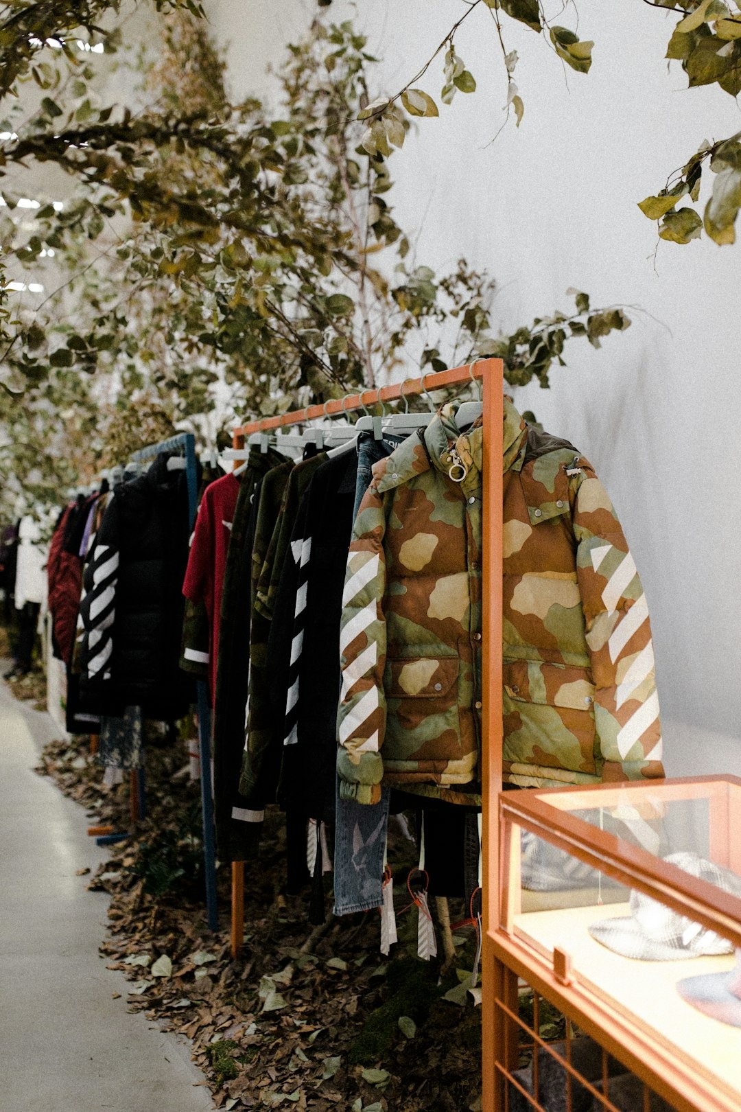 Clothing rack with striped apparel and camouflage jacket.